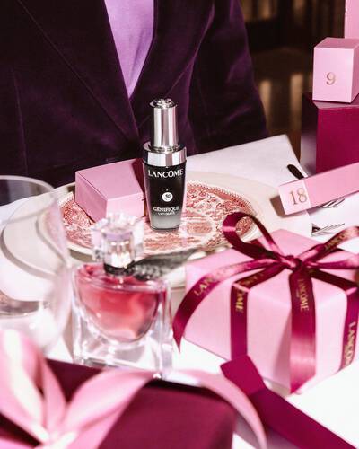 Продукти за красота Lancome и розови подаръчни кутии, аранжирани на празнична маса.