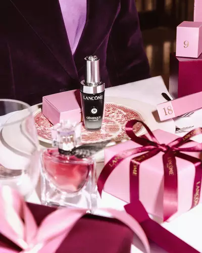 Продукти за красота Lancome и розови подаръчни кутии, аранжирани на празнична маса.