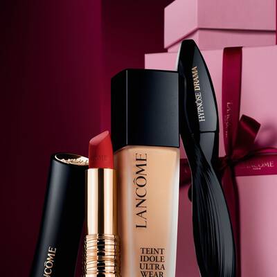 Изискано изображение на матово червило Lancome L'Absolu Rouge, фон дьо тен Teint Idole Ultra Wear и спирала Hypnose Drama на луксозен тъмночервен празничен фон.