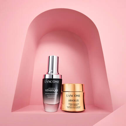 Два козметични продукта на Lancome, разположени в арка от розов фон, включващи серум и крем за лице.