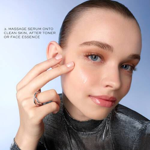 Млада жена с гладка кожа нанася серум на лицето си, след тонер, усмихната на неутрален фон.