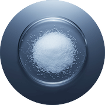 Снежнобял кристален сол в стъклена чиния на тъмен фон.