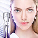 Жена с ясна кожа и светли очи, до бутилка серум на Lancome на фона на нежни линии.