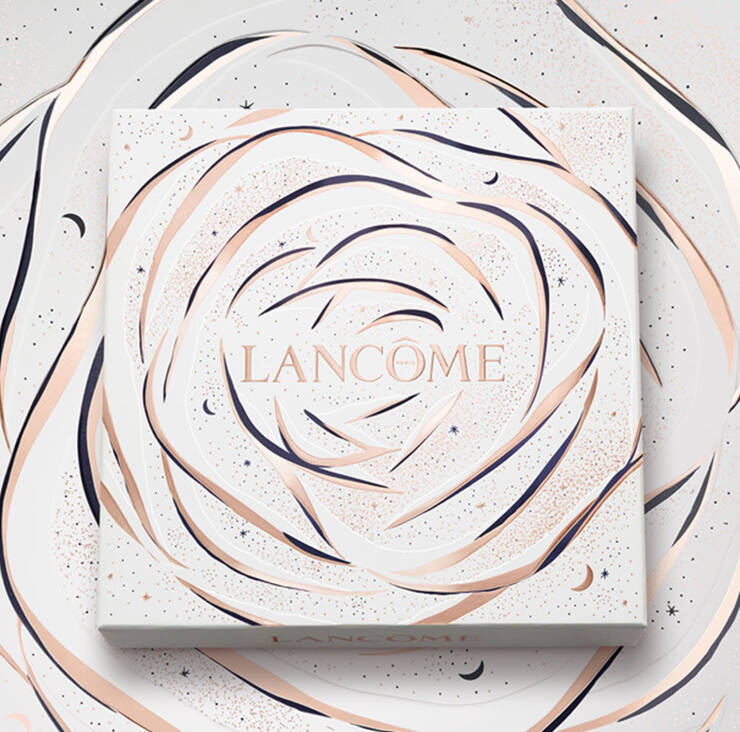 A decorative box featuring the word "LANCOME" in elegant lettering, surrounded by a swirling rose design in soft colors against a textured background.