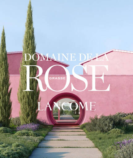 Сграда в розов цвят, обградена от растения и храсти, с надпис "Domaine de la Rose Lancome Париж".