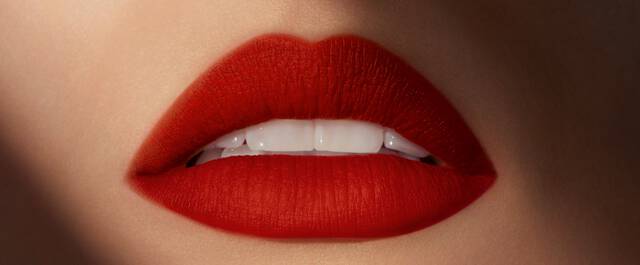 Close-up of a pair of perfectly shaped lips with a vivid red lipstick, showcasing smooth texture and a subtle shine.